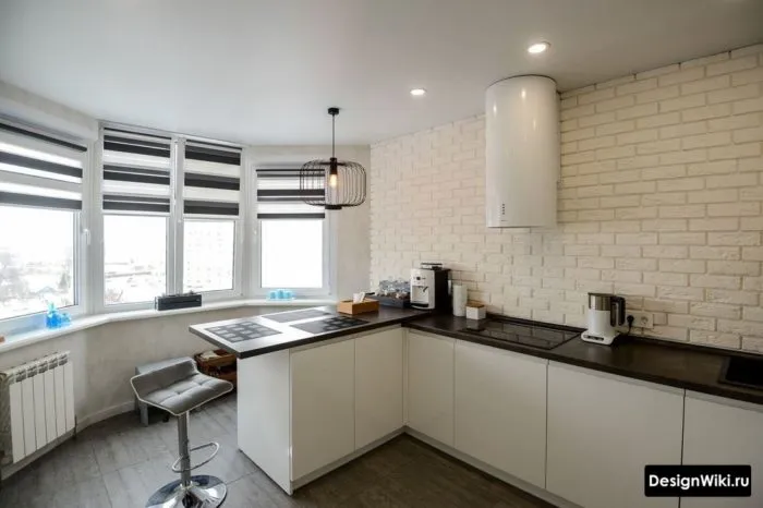 Белая кухня без верхних шкафов с черно-белыми рулонными шторами